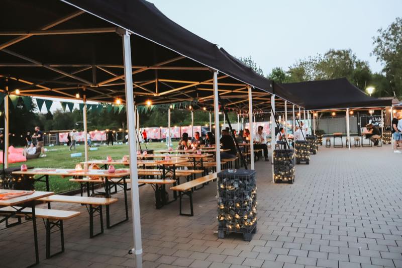 Biertische unter Pavillons mit Lichterketten am Abend